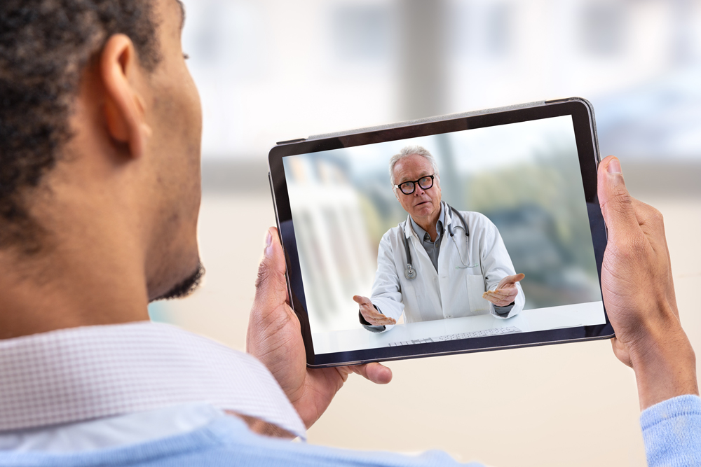 Man watching a senior doctor on a tablet